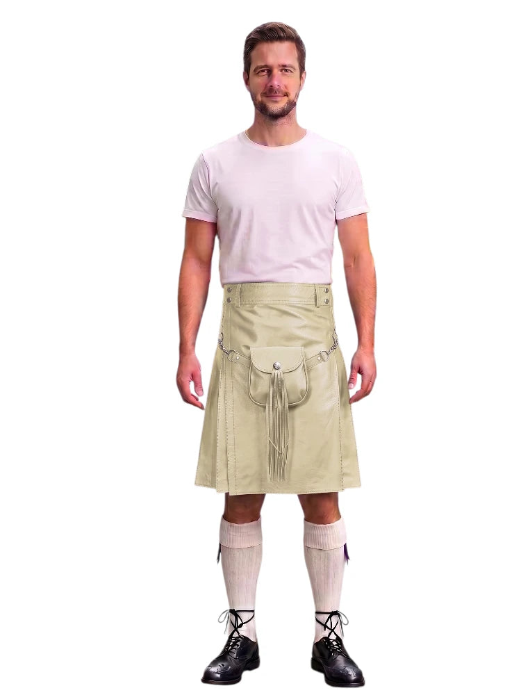 A man modeling a beige kilt with a front pouch and tassel detail, paired with a light pink t-shirt, cream knee socks, and black lace-up shoes, against a plain white background.