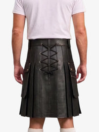 A man wearing a black faux-leather kilt with a lace-up back, side pockets, and pleated front, paired with a white t-shirt and white socks, shown from the back against a white background.