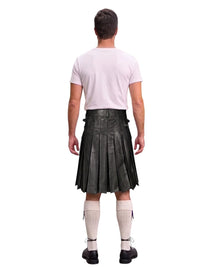 A man shown from the back wearing a black leather kilt, a light pink t-shirt, cream-colored knee-high socks, and black shoes, set against a plain white background.