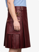 Burgundy leather kilt with gold buckles worn by a person on a white background