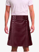 A person wearing a dark burgundy faux-leather kilt with silver-tone metal hardware, belt loops, and side pockets, paired with a light pink t-shirt against a plain white background.