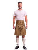 A man modeling a tan faux-leather kilt with a matching belt and pouch, paired with a white t-shirt, white knee-high socks, and black lace-up shoes, against a plain white background.