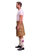 A man shown in profile wearing a tan leather kilt, a white t-shirt, white socks with a purple accent, and black shoes, photographed against a plain white background.