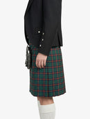 Person wearing a black blazer and green plaid kilt on a white background