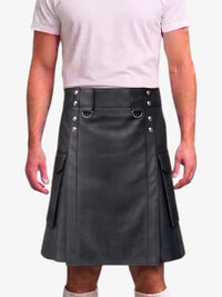 A man wearing a black faux-leather kilt with silver-tone metal hardware, a matching belt, and side cargo pockets, paired with a light pink t-shirt against a plain white background.
