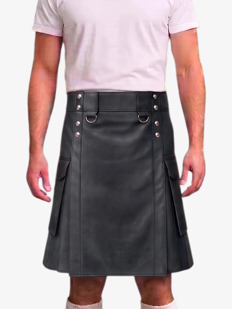 A man wearing a black faux-leather kilt with silver-tone metal hardware, a matching belt, and side cargo pockets, paired with a light pink t-shirt against a plain white background.