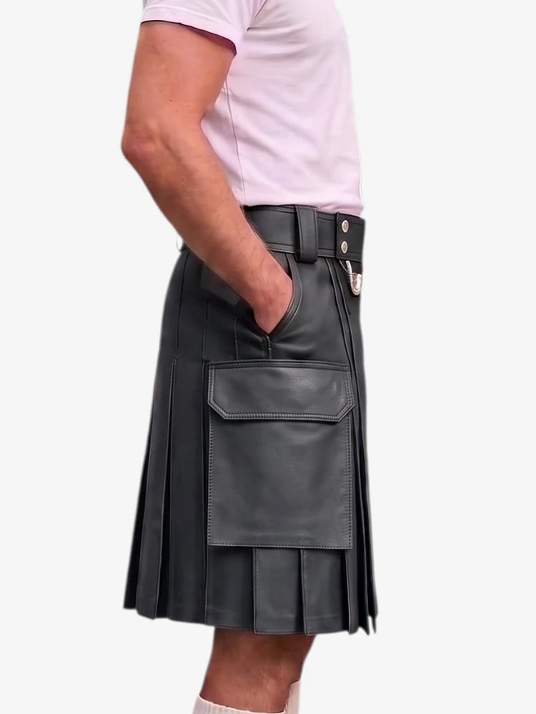 A black faux-leather kilt with pleated detailing, a belt, and a large front flap pocket, shown on a model wearing a light pink t-shirt against a white background.