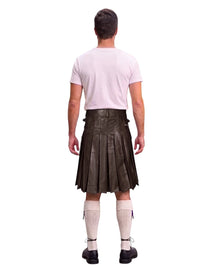 A man shown from the back wearing a dark brown leather kilt, a light pink t-shirt, cream-colored knee-high socks, and black shoes, isolated on a white background.