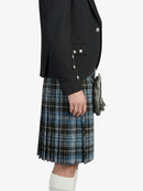 Person wearing a black blazer and blue plaid kilt on a white background