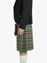 Person wearing a black blazer and green plaid kilt on a white background