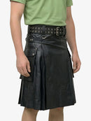 Person wearing a black leather kilt with a green shirt on a white background