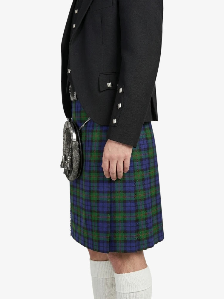 Person wearing a black blazer and plaid kilt on a white background