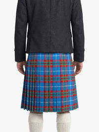Person wearing a black coat and blue plaid kilt on a white background