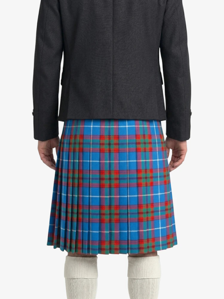 Person wearing a black coat and blue plaid kilt on a white background