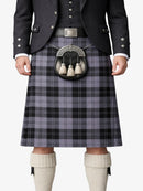 Person wearing a traditional Scottish kilt with a patterned belt and jacket on a white background