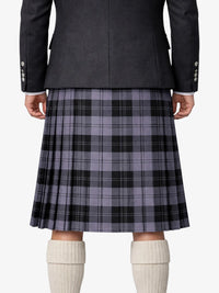 Person wearing a gray plaid kilt with a dark jacket on a white background