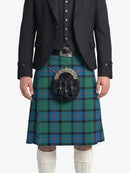 Person wearing a green plaid kilt with a black jacket on a white background