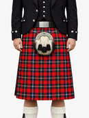 Person wearing a red tartan kilt with a black jacket on a white background