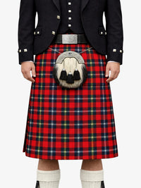 Person wearing a red tartan kilt with a black jacket on a white background
