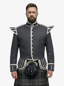 Man wearing a dark gray jacket with white trim and a grey watch tartan kilt on a white background