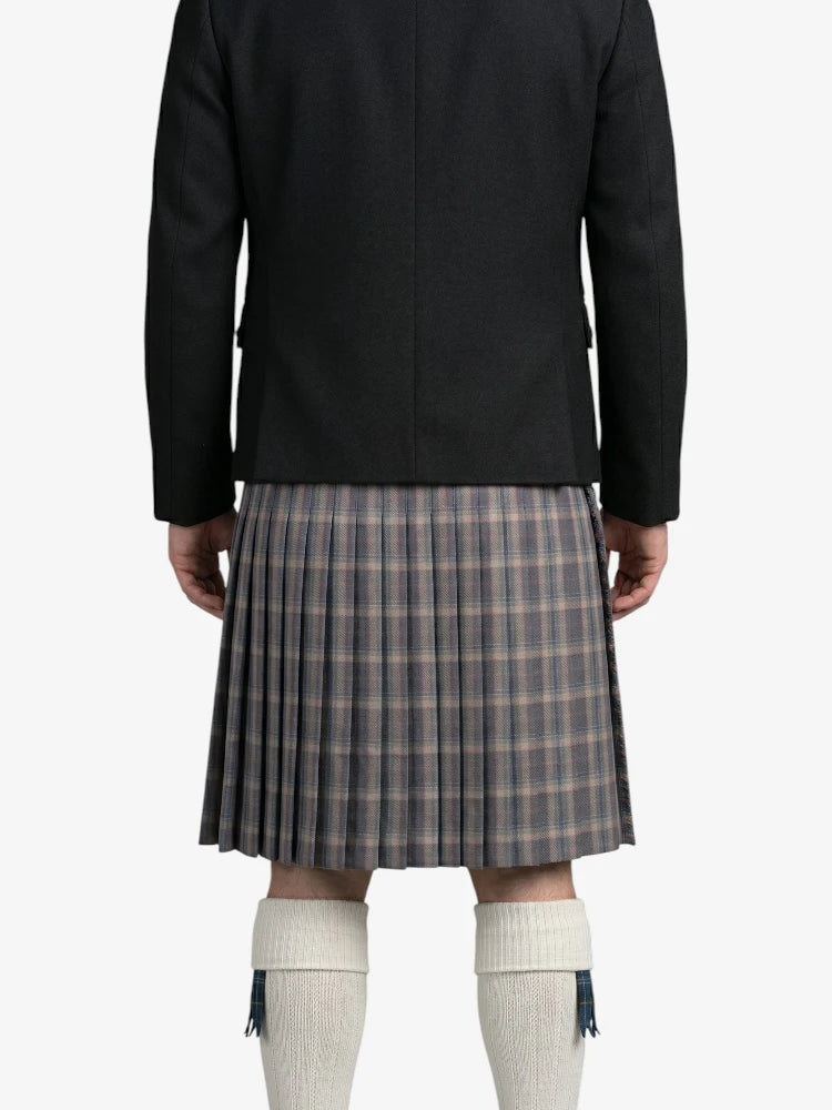 Person wearing a black coat and plaid kilt on a white background
