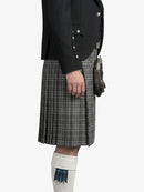 Person wearing a black jacket and gray plaid kilt on a white background