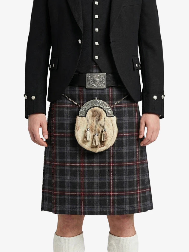 Person wearing a traditional Scottish kilt with a black jacket and white shirt on a white background