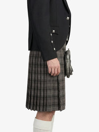 Person wearing a black jacket and plaid kilt on a white background