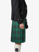 Person wearing a black jacket and green plaid kilt on a white background