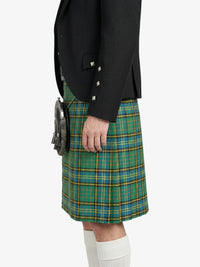 Person wearing a black jacket and green plaid kilt on a white background