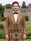 A man wearing a traditional Scottish formal outfit with a tan jacket, white shirt, black bow tie, and a brown tartan kilt with a sporran, standing outdoors in front of a stone mansion.