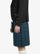 Person wearing a black jacket and green plaid kilt on a white background