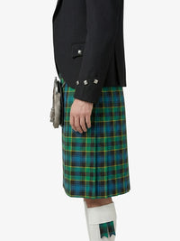 Person wearing a black jacket and green plaid kilt on a white background