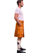 A man shown in profile wearing a tan leather kilt, a light pink t-shirt, white socks, and black shoes, isolated on a white background.