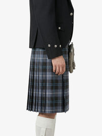 Person wearing a black jacket and plaid kilt on a white background