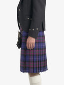 Person wearing a dark gray blazer and a purple plaid kilt on a white background