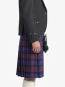 Person wearing a dark gray blazer and a purple plaid kilt on a white background