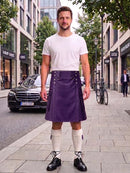 A man stands on a city sidewalk wearing a purple leather kilt, a white t-shirt, white knee-high socks, and black leather shoes. The background shows a street with buildings, a black Mercedes-Benz car, and a bicycle.