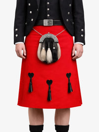 Person wearing a red kilt with decorative heart and a black jacket on a white background