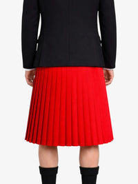 Person wearing a black jacket and red pleated kilt on a white background