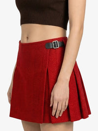 Red pleated skirt with a black belt on a white background
