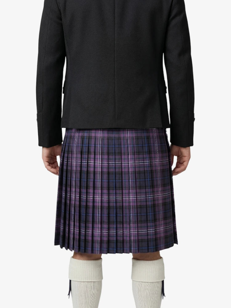 Person wearing a black jacket and purple plaid kilt on a white background