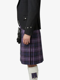 Person wearing a black jacket and purple plaid kilt on a white background