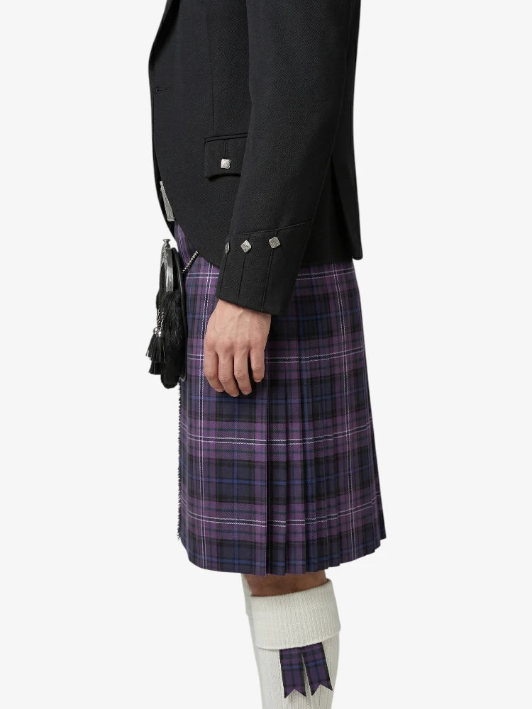 Person wearing a black jacket and purple plaid kilt on a white background