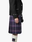 Person wearing a black jacket and purple plaid kilt on a white background