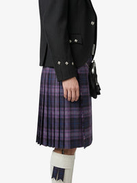 Person wearing a black jacket and purple plaid kilt on a white background