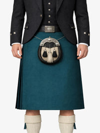Person wearing a dark jacket, teal kilt, and white socks on a white background