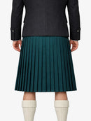 Person wearing a dark coat and green pleated kilt on a white background