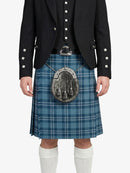 Person wearing a black jacket, blue plaid kilt, and white knee-high socks on a white background
