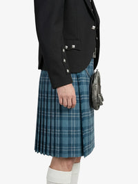 Person wearing a black jacket and blue plaid kilt on a white background